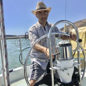 A Man, the Captain, sitting on the Helm of Boat steering the Vessel and about to adjust the Speed - CO88.co