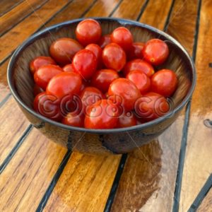 Delicious Organic Cherry Tomatoes in Japanese Stoneware Bowl on recently Varnished Teak Boat Deck - CO88.co